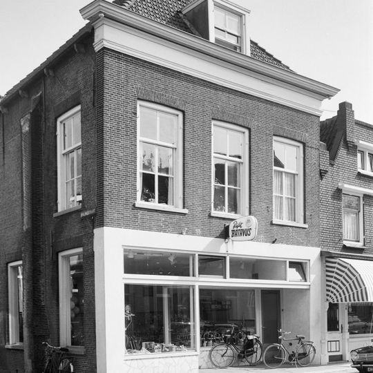 Markant hoekpand met verdieping en schilddak. Eenvoudige lijstgevel, waarin vensters met zesruitsschuiframen