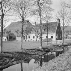 Kop-hals-rompboerderij met lang voorhuis met omlijste ingang met pilasters in de lange gevel