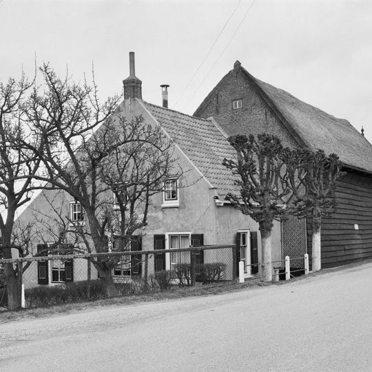 Boerderij, bestaande uit een gepleisterd woonhuis onder pannen zadeldak, evenwijdig aan de dijk.