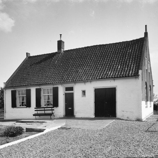 Huis onder zadeldak tussen zijtopgevels, 9-ruitsvensters aan de voorzijde. Gedeeltelijk wit geverfd