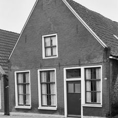 Pand tegen topgevel met deklijsten en zes- en vierruitsvensters onder zadeldak met topschoorsteen