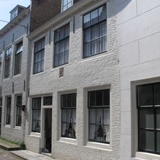 Huis met geverfde rechte gevel met gootlijst op klossen