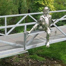 Kovová plastika vodníka na lávce přes potok Popelka v Nové Vsi nad Popelkou