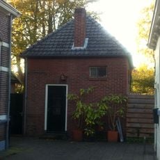 Eenvoudig vierkant ritueel badhuisje van bruine baksteen onder een met grijze friese pannen gedekt tentdak